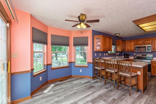 1159 Oak Leaf Rd, Franklin, IN 46131 - kitchen featuring appliances with stainless steel finishes, brown cabinetry, ceiling fan, light wood-type flooring, and a textured ceiling