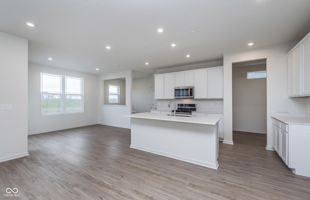7151 Firestone Rd, Whitestown, IN 46052 - kitchen featuring appliances with stainless steel finishes, light countertops, light wood-style flooring, a kitchen island with sink, and recessed lighting