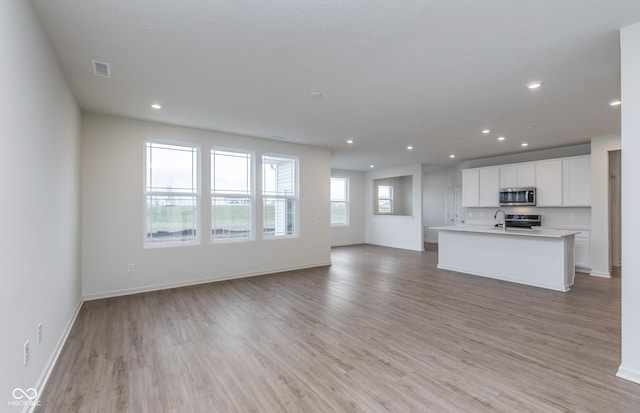 7151 Firestone Rd, Whitestown, IN 46052 - unfurnished living room featuring light wood-type flooring, recessed lighting, baseboards, and a sink