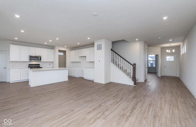 7151 Firestone Rd, Whitestown, IN 46052 - kitchen with stainless steel microwave, range, open floor plan, light wood finished floors, and recessed lighting