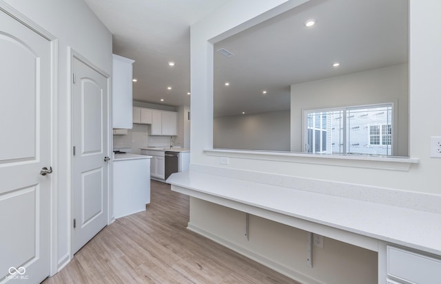 7151 Firestone Rd, Whitestown, IN 46052 - kitchen featuring stainless steel dishwasher, light countertops, white cabinets, light wood-style floors, and recessed lighting