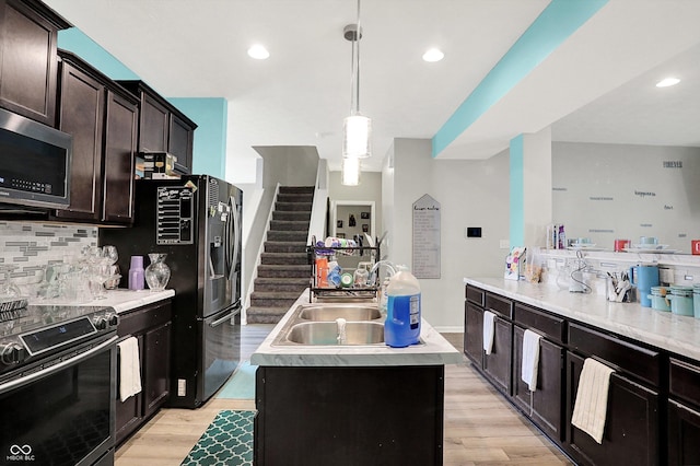 10902 Jimmy Lake Dr, Indianapolis, IN 46239 - kitchen with appliances with stainless steel finishes, a kitchen island with sink, light wood-style flooring, tasteful backsplash, and light countertops