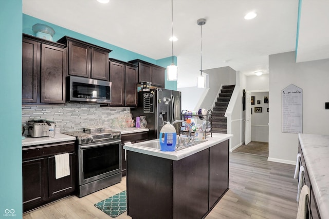 10902 Jimmy Lake Dr, Indianapolis, IN 46239 - kitchen with appliances with stainless steel finishes, tasteful backsplash, light countertops, light wood finished floors, and dark brown cabinetry