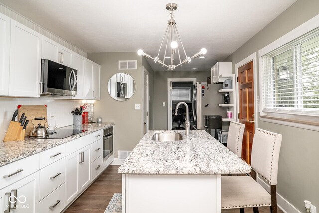 6180 Winnpeny Ln, Indianapolis, IN 46220 - kitchen with appliances with stainless steel finishes, a sink, tasteful backsplash, a center island with sink, and a breakfast bar area