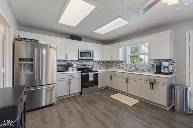 6608 Sonesta Dr, Indianapolis, IN 46217 - kitchen featuring appliances with stainless steel finishes, backsplash, dark wood-type flooring, light countertops, and white cabinets