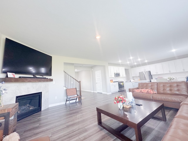 2358 S Stonehill Way, New Palestine, IN 46163 - living room featuring light wood finished floors, a tile fireplace, and stairway