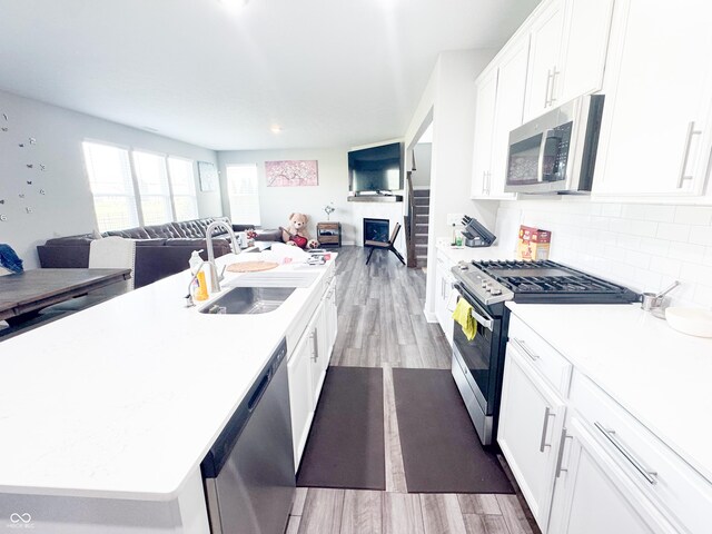 2358 S Stonehill Way, New Palestine, IN 46163 - kitchen featuring appliances with stainless steel finishes, open floor plan, a center island with sink, wood finished floors, and white cabinets