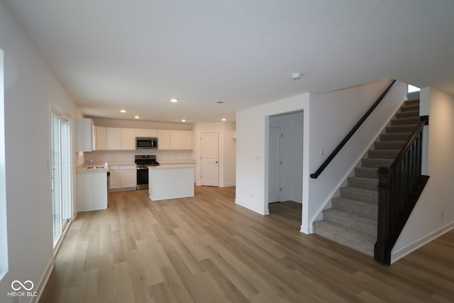 3917 Highcrest Rd, Indianapolis, IN 46239 - unfurnished living room featuring light wood-style floors, stairs, a sink, baseboards, and recessed lighting