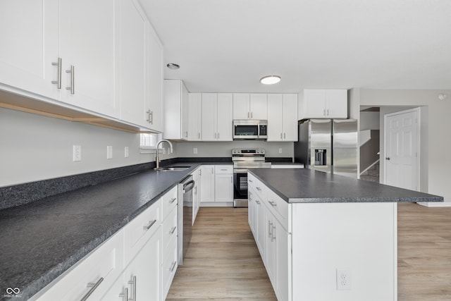 9949 Nightsong Ln, Avon, IN 46123 - kitchen with stainless steel appliances, a sink, dark countertops, light wood-type flooring, and white cabinets