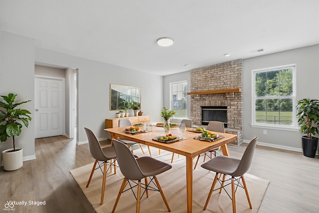 9949 Nightsong Ln, Avon, IN 46123 - dining area featuring plenty of natural light, baseboards, light wood-type flooring, and a brick fireplace