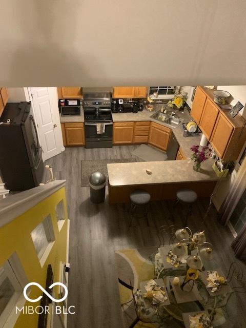 6730 NW Shanghai Cir, Indianapolis, IN 46268 - kitchen with electric stove, light wood finished floors, light countertops, and a breakfast bar area