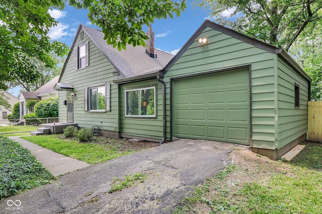 4708 Haverford Ave, Indianapolis, IN 46205 - view of front facade featuring roof with shingles, a chimney, asphalt driveway, and an attached garage