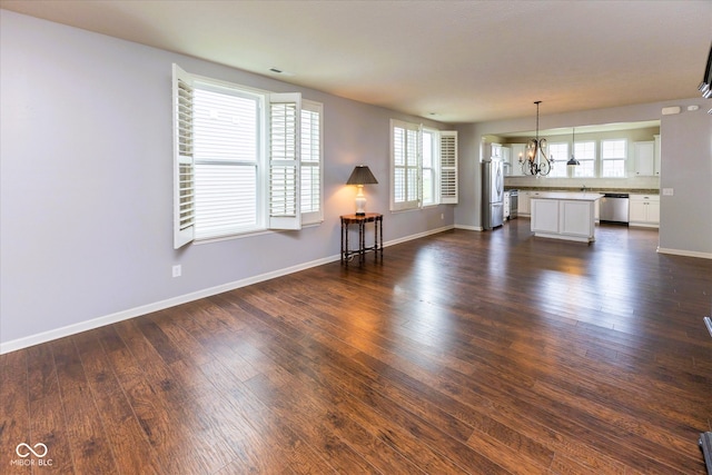 12820 Gloria Dr, Fishers, IN 46037 - unfurnished living room featuring a chandelier, dark wood-type flooring, and healthy amount of natural light