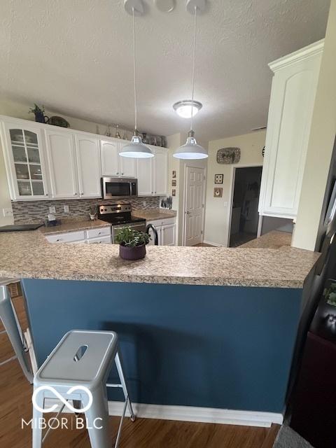5304 Appleseed Way, Indianapolis, IN 46217 - kitchen with stainless steel appliances, a textured ceiling, white cabinetry, tasteful backsplash, and dark wood-type flooring