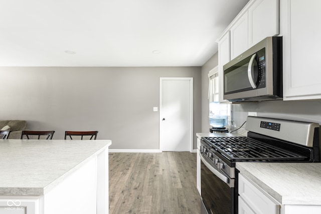 258 N Green Springs Rd, Indianapolis, IN 46214 - kitchen featuring appliances with stainless steel finishes, light wood-type flooring, light countertops, and white cabinets