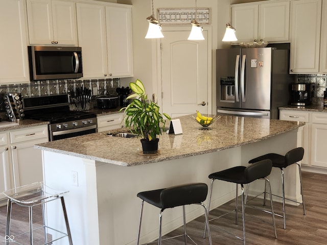 6731 Keepsake Dr, Whitestown, IN 46075 - kitchen featuring appliances with stainless steel finishes, backsplash, white cabinetry, and a kitchen island with sink