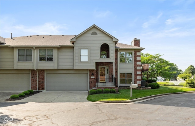 8955 Stonegate Rd Unit A, Indianapolis, IN 46227 - view of front of house featuring a chimney, driveway, a garage, brick siding, and a front lawn