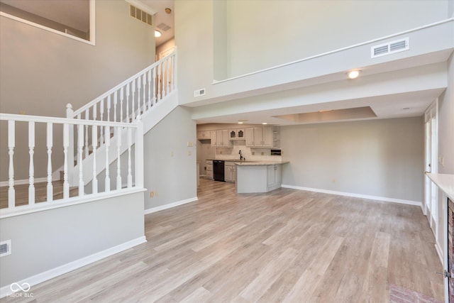 8955 Stonegate Rd Unit A, Indianapolis, IN 46227 - unfurnished living room featuring a towering ceiling, light wood-type flooring, and stairs