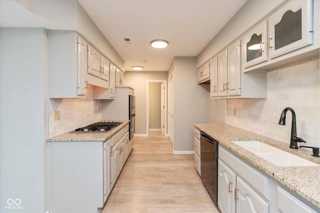 8955 Stonegate Rd Unit A, Indianapolis, IN 46227 - kitchen with stainless steel gas stovetop, black dishwasher, light wood finished floors, backsplash, and light stone countertops