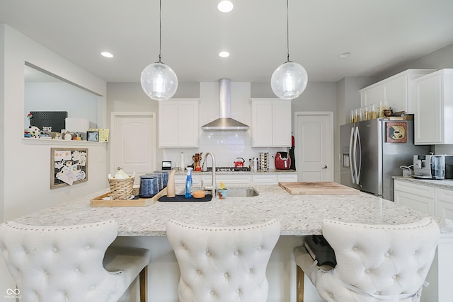 15598 Memorial Way, Fishers, IN 46037 - kitchen featuring wall chimney exhaust hood, a kitchen bar, a center island with sink, stainless steel fridge, and decorative backsplash