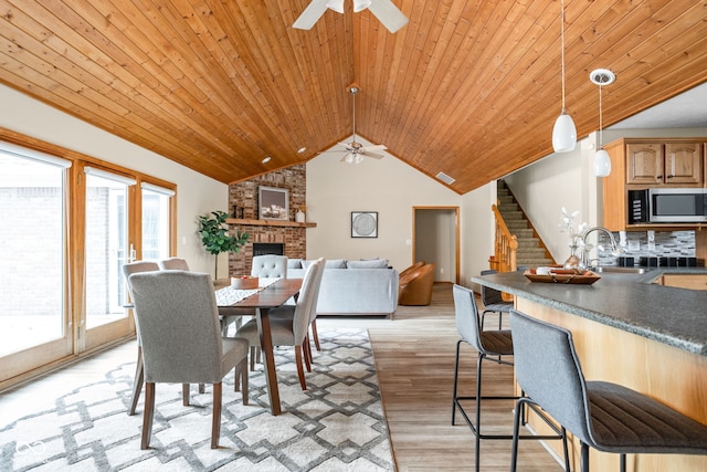 5695 N Red Oak Dr, Greenfield, IN 46140 - dining room with a ceiling fan, stairs, light wood-style flooring, wooden ceiling, and a brick fireplace