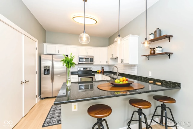 721 E N St Unit 2C, Indianapolis, IN 46202 - kitchen with stainless steel appliances, a peninsula, light wood finished floors, tasteful backsplash, and white cabinets