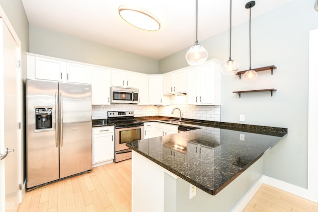 721 E N St Unit 2C, Indianapolis, IN 46202 - kitchen featuring stainless steel appliances, a peninsula, tasteful backsplash, dark stone countertops, and white cabinetry