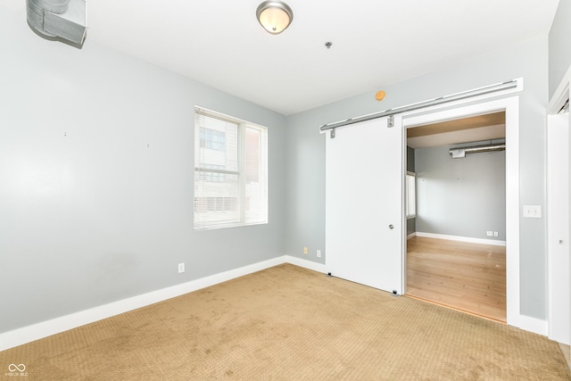 721 E N St Unit 2C, Indianapolis, IN 46202 - unfurnished bedroom featuring a barn door, carpet floors, and a closet