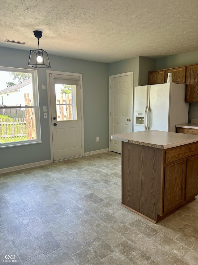 12307 Chiseled Stone Dr, Fishers, IN 46037 - kitchen with white fridge with ice dispenser, baseboards, light countertops, brown cabinetry, and a textured ceiling