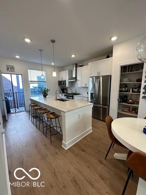 751 Switchyard Pl, Indianapolis, IN 46202 - kitchen featuring stainless steel appliances, wall chimney range hood, wood finished floors, a sink, and recessed lighting