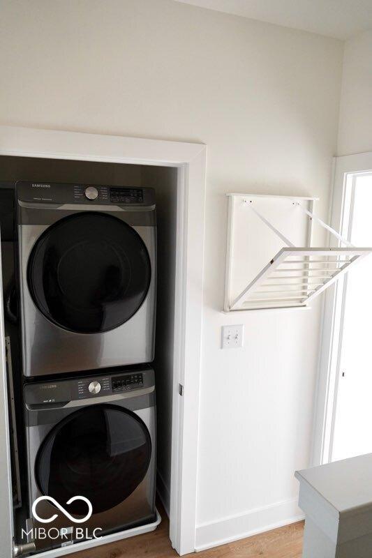 751 Switchyard Pl, Indianapolis, IN 46202 - laundry room featuring stacked washer and clothes dryer, wood finished floors, and baseboards