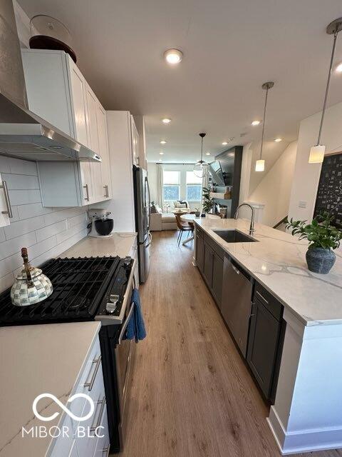 751 Switchyard Pl, Indianapolis, IN 46202 - kitchen with wall chimney exhaust hood, a sink, appliances with stainless steel finishes, light wood-style floors, and backsplash