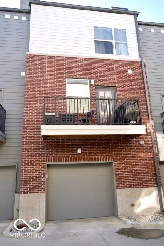751 Switchyard Pl, Indianapolis, IN 46202 - back of property with brick siding, an attached garage, and a balcony