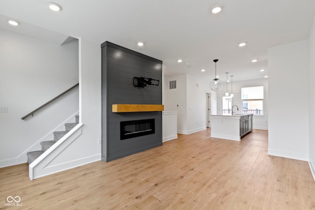 751 Switchyard Pl, Indianapolis, IN 46202 - unfurnished living room featuring recessed lighting, a fireplace, light wood finished floors, stairs, and baseboards