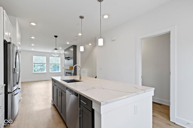 751 Switchyard Pl, Indianapolis, IN 46202 - kitchen with appliances with stainless steel finishes, a sink, light wood finished floors, a center island with sink, and light stone countertops