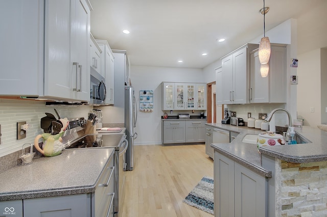 214 W Stoney Trl, Greenfield, IN 46140 - kitchen with appliances with stainless steel finishes, a peninsula, light wood-style flooring, decorative backsplash, and glass insert cabinets