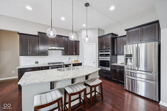 10806 Solis Cir, Fishers, IN 46038 - kitchen with appliances with stainless steel finishes, under cabinet range hood, dark wood-style floors, dark brown cabinetry, and a kitchen breakfast bar