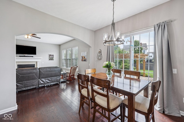 10806 Solis Cir, Fishers, IN 46038 - dining space with arched walkways, dark wood finished floors, a chandelier, and a fireplace
