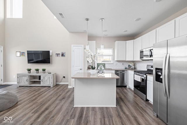 2892 Maricopa Blvd, Whitestown, IN 46075 - kitchen featuring appliances with stainless steel finishes, a kitchen island, white cabinets, dark wood-style floors, and backsplash