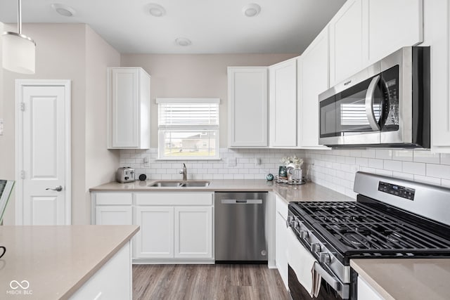 2892 Maricopa Blvd, Whitestown, IN 46075 - kitchen with stainless steel appliances, light wood-style flooring, backsplash, white cabinetry, and decorative light fixtures