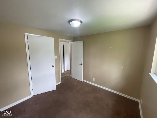 1749 N Graham Ave, Indianapolis, IN 46218 - unfurnished bedroom with dark carpet and baseboards