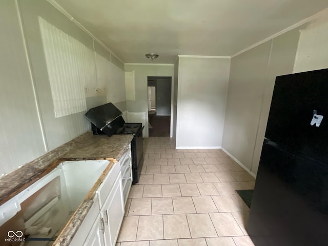 9045 Stardust Dr, Indianapolis, IN 46229 - kitchen with freestanding refrigerator, white cabinetry, dark stone countertops, light tile patterned floors, and crown molding