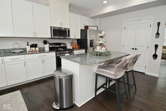 13616 Whitten Dr N, Fishers, IN 46037 - kitchen with appliances with stainless steel finishes, dark wood finished floors, a breakfast bar area, recessed lighting, and white cabinets