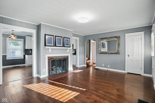 808 N Layman Ave, Indianapolis, IN 46219 - unfurnished living room with ornamental molding, arched walkways, dark wood finished floors, and a fireplace