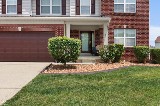 10312 Gladeview Dr, Indianapolis, IN 46239 - view of exterior entry with brick siding, a lawn, a garage, and concrete driveway
