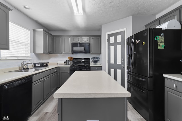 10312 Gladeview Dr, Indianapolis, IN 46239 - kitchen with black appliances, gray cabinets, light wood-style floors, a center island, and a textured ceiling
