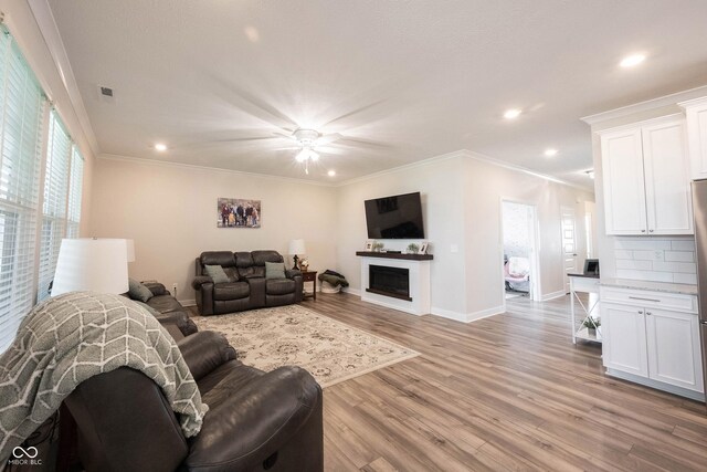 9671 Holborn Ave, Mccordsville, IN 46055 - living area with light wood-style floors, recessed lighting, a fireplace, ceiling fan, and crown molding