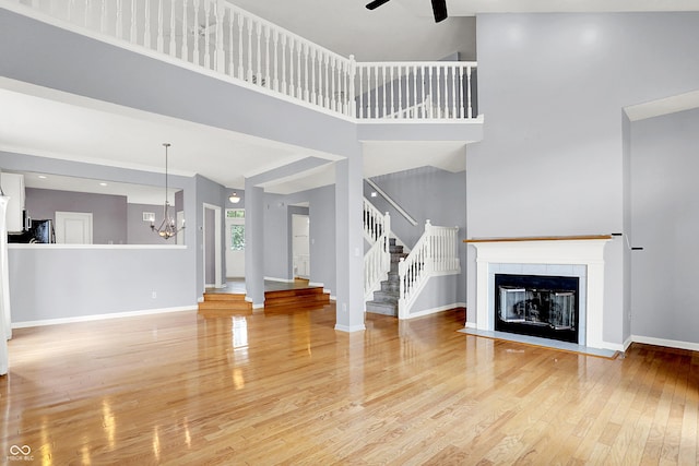 4810 Crystal River Ct, Indianapolis, IN 46240 - unfurnished living room featuring wood finished floors, a high ceiling, stairway, ceiling fan, and a tiled fireplace