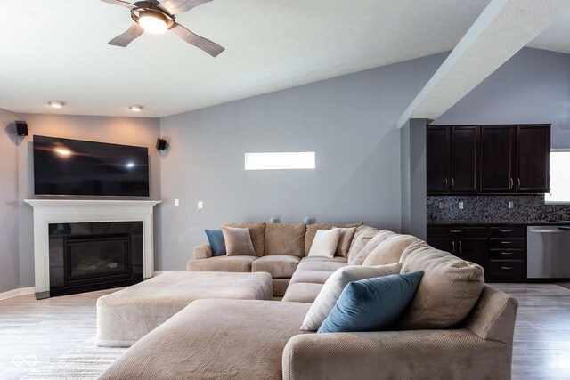 4353 W Parkway Ct, New Palestine, IN 46163 - living room featuring light wood-type flooring, a ceiling fan, a glass covered fireplace, vaulted ceiling, and baseboards