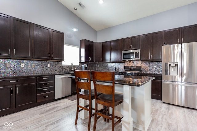 4353 W Parkway Ct, New Palestine, IN 46163 - kitchen featuring appliances with stainless steel finishes, dark brown cabinets, a kitchen bar, light wood-style floors, and lofted ceiling